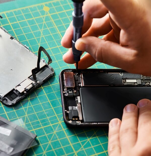 partial view of technician using screwdriver on mobile phone in professional repair workshop