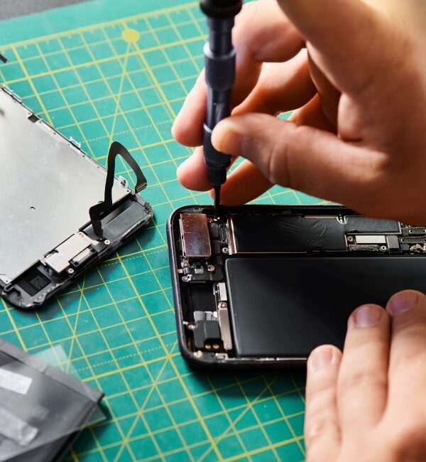 partial view of technician using screwdriver on mobile phone in professional repair workshop