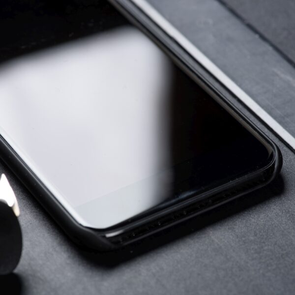 close up of smartphone with ruler and office supplies isolated on black