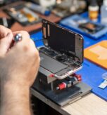 A skilled technician performs phone repair and replaces a battery in a well-organized workshop with tools and parts readily available.